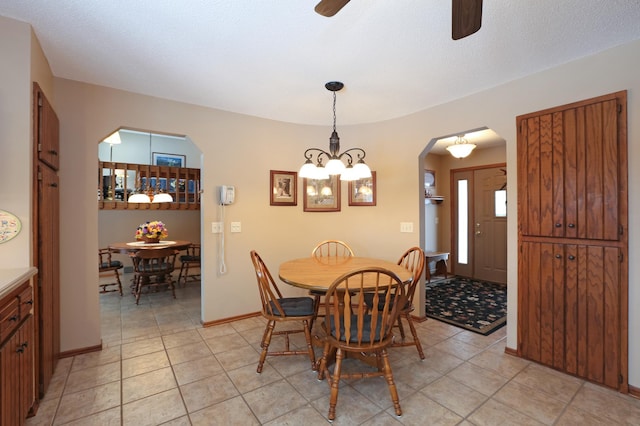 tiled dining area featuring ceiling fan with notable chandelier