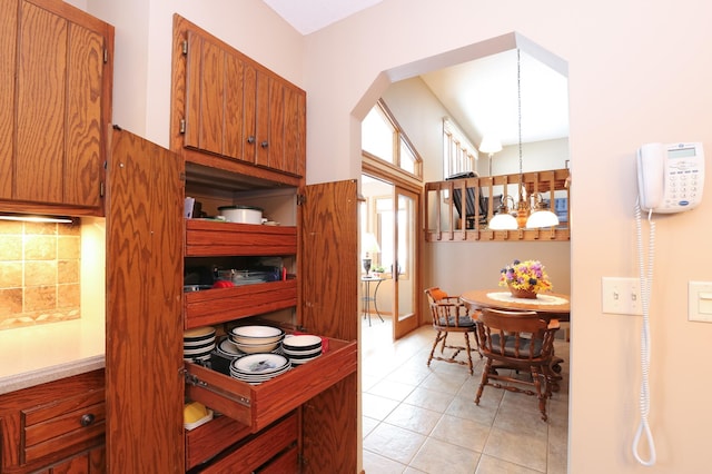 kitchen featuring hanging light fixtures, light tile patterned flooring, a chandelier, and decorative backsplash