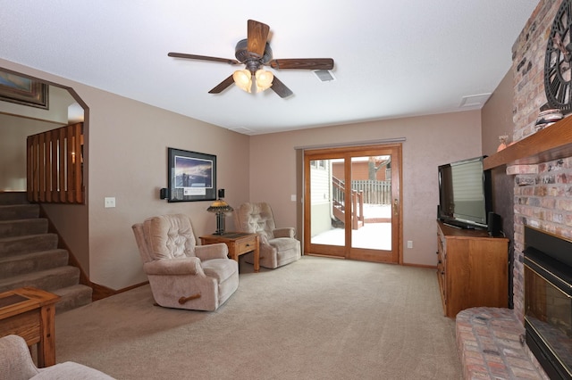 living room featuring a brick fireplace, light colored carpet, and ceiling fan