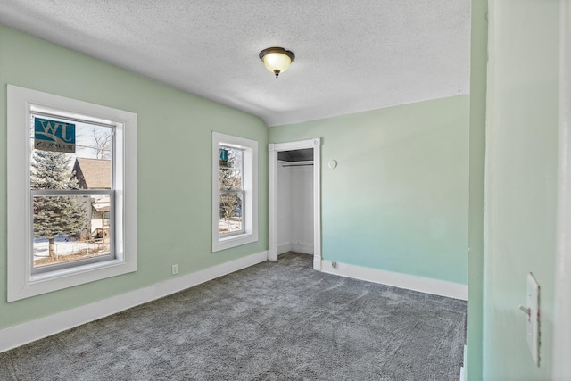 unfurnished bedroom featuring a closet, dark colored carpet, and a textured ceiling