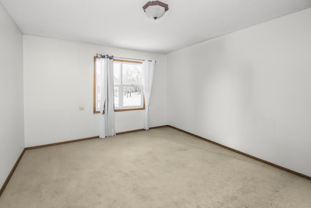 unfurnished room with light carpet and baseboards