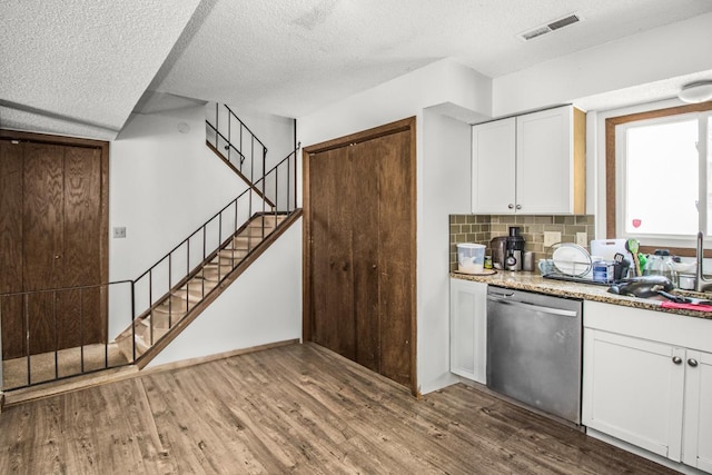 kitchen with tasteful backsplash, visible vents, white cabinets, dishwasher, and wood finished floors