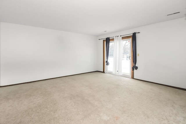 spare room featuring visible vents and light colored carpet