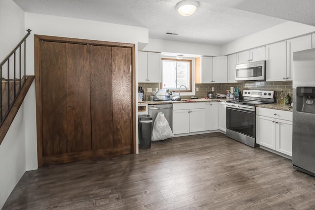 kitchen featuring stainless steel appliances, dark wood-type flooring, a sink, and white cabinetry