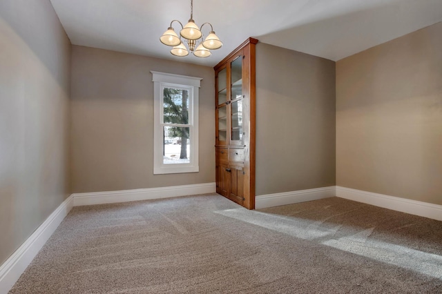 carpeted empty room with a notable chandelier