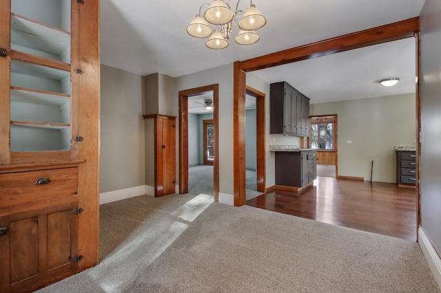 interior space featuring ceiling fan with notable chandelier and dark carpet