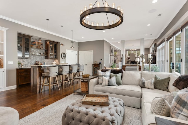 living room with dark wood-type flooring, crown molding, and a notable chandelier