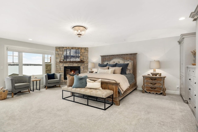 bedroom with light carpet, a stone fireplace, and a water view