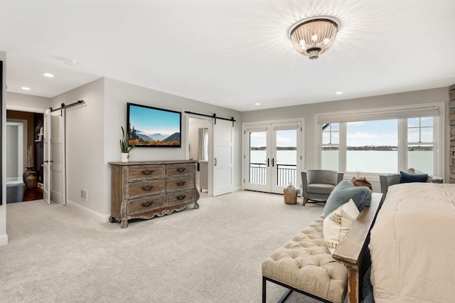 bedroom featuring french doors, a barn door, light carpet, and access to exterior