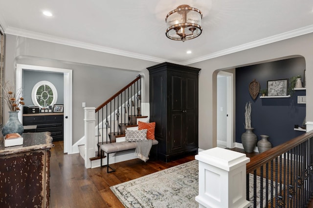 foyer with an inviting chandelier, dark wood-type flooring, and ornamental molding