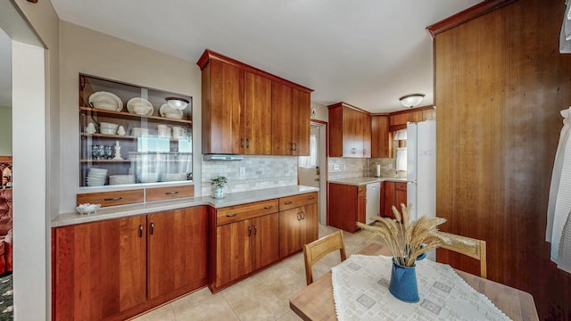 kitchen featuring tasteful backsplash, light tile patterned floors, stainless steel dishwasher, and white refrigerator