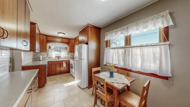 kitchen featuring sink, light tile patterned floors, backsplash, and white appliances