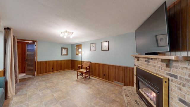 living area featuring a brick fireplace and wood walls