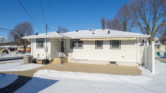 snow covered rear of property featuring central AC unit