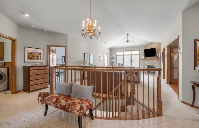 hallway with light tile patterned floors, washer / dryer, vaulted ceiling, and a notable chandelier