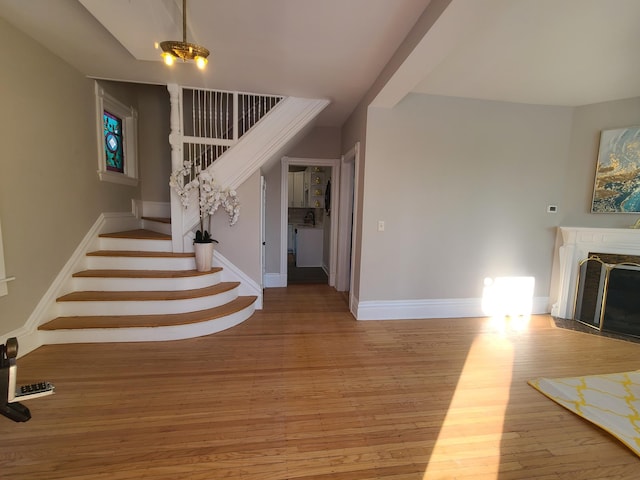 stairway with a fireplace and hardwood / wood-style floors