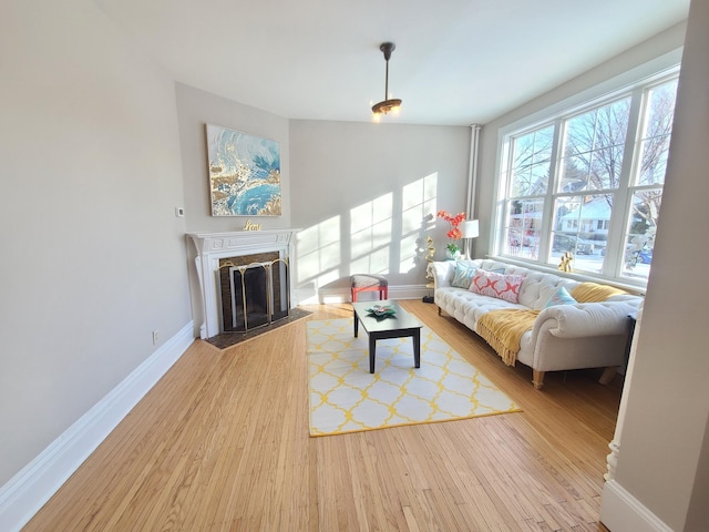 living room with lofted ceiling, a fireplace, and light hardwood / wood-style floors