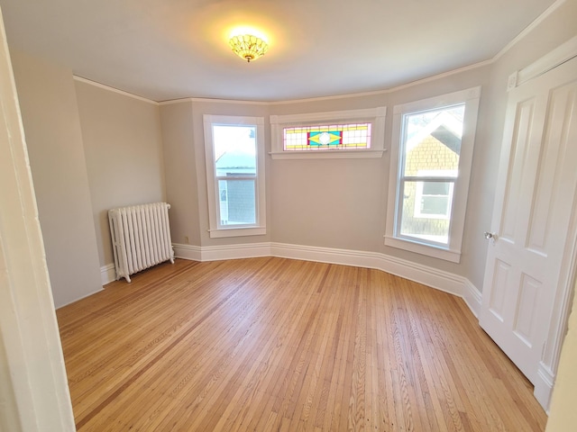 unfurnished room with crown molding, radiator heating unit, and light hardwood / wood-style floors