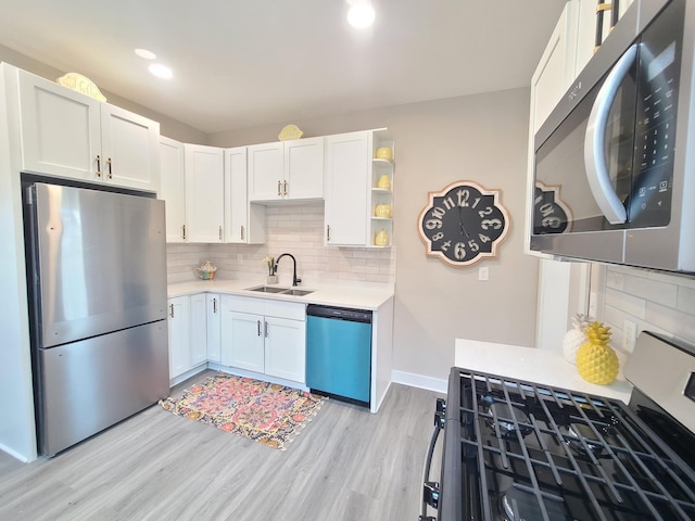 kitchen with appliances with stainless steel finishes, sink, white cabinets, and light wood-type flooring