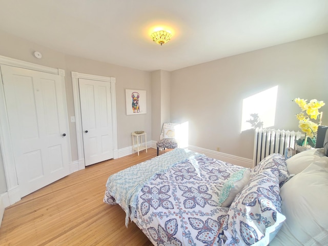 bedroom with radiator heating unit and light wood-type flooring