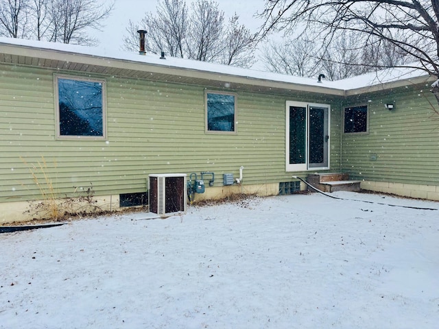 snow covered back of property featuring cooling unit