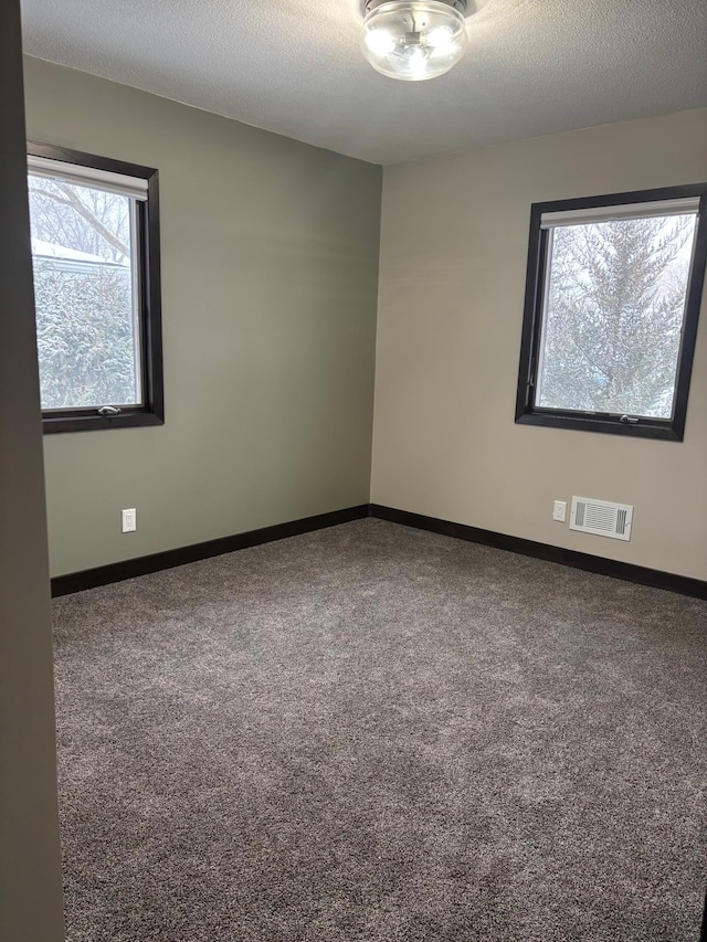 carpeted empty room featuring a textured ceiling