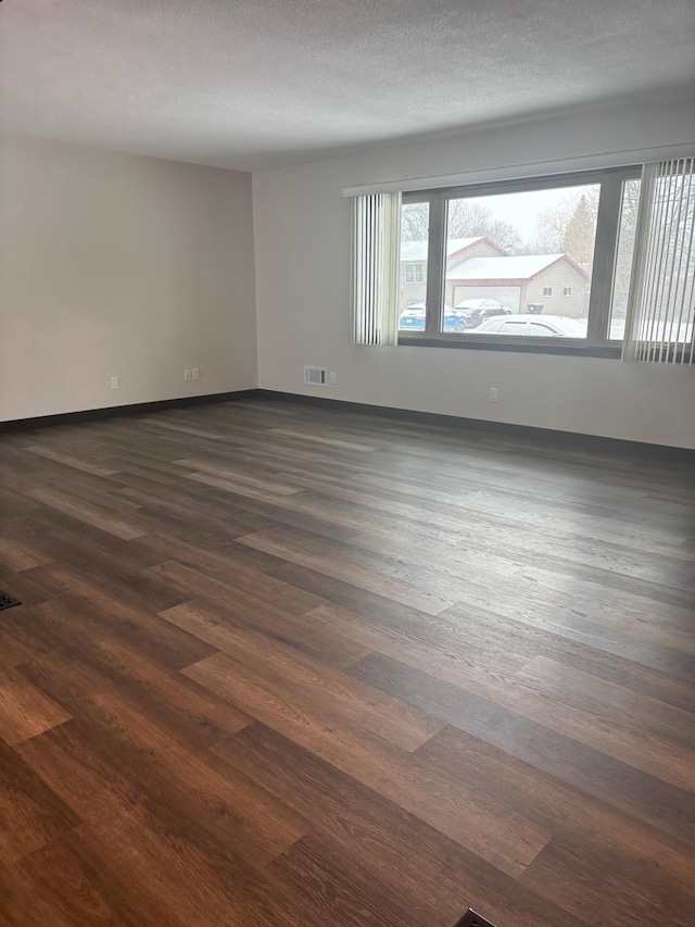 spare room featuring dark wood-type flooring and a textured ceiling