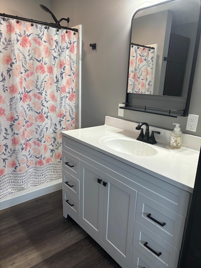 bathroom with walk in shower, vanity, and wood-type flooring