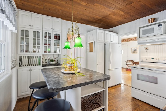 kitchen with dark countertops, white appliances, glass insert cabinets, and white cabinetry