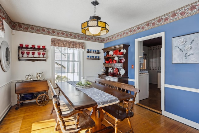 dining area featuring a textured ceiling, light wood-style flooring, and baseboards