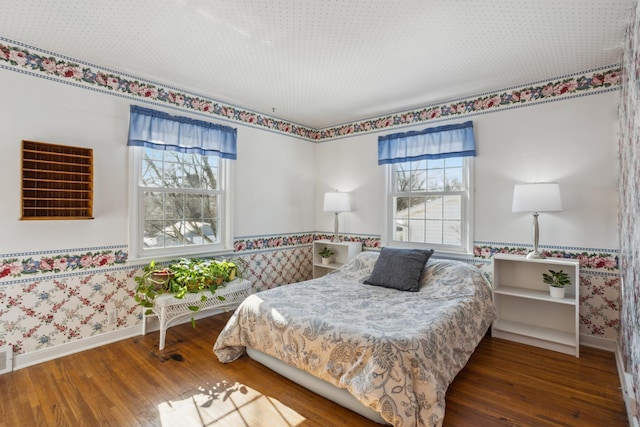 bedroom featuring wallpapered walls, multiple windows, and dark wood finished floors