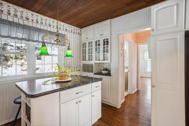 kitchen featuring dark countertops, wooden ceiling, glass insert cabinets, and white cabinets