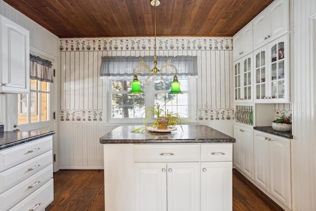 kitchen featuring a center island, pendant lighting, dark countertops, glass insert cabinets, and white cabinetry