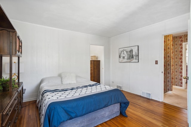 bedroom with dark wood-style flooring, visible vents, and a decorative wall