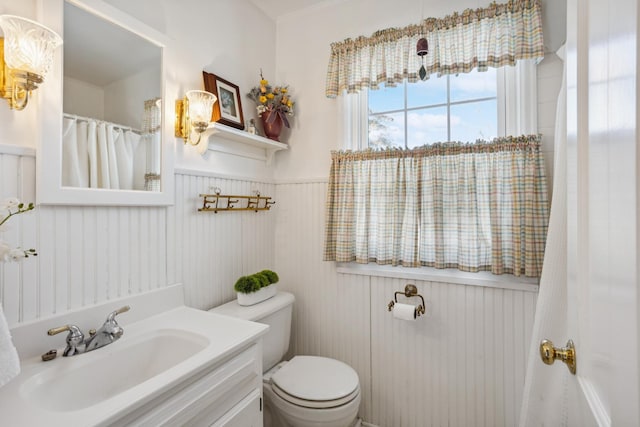 bathroom with toilet, a wainscoted wall, and vanity