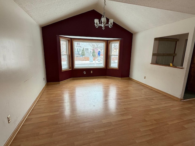 unfurnished room featuring wood-type flooring, vaulted ceiling, a notable chandelier, and a textured ceiling