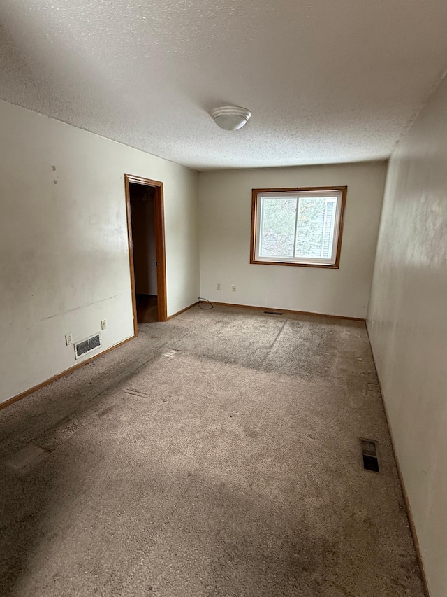 empty room featuring a textured ceiling and carpet