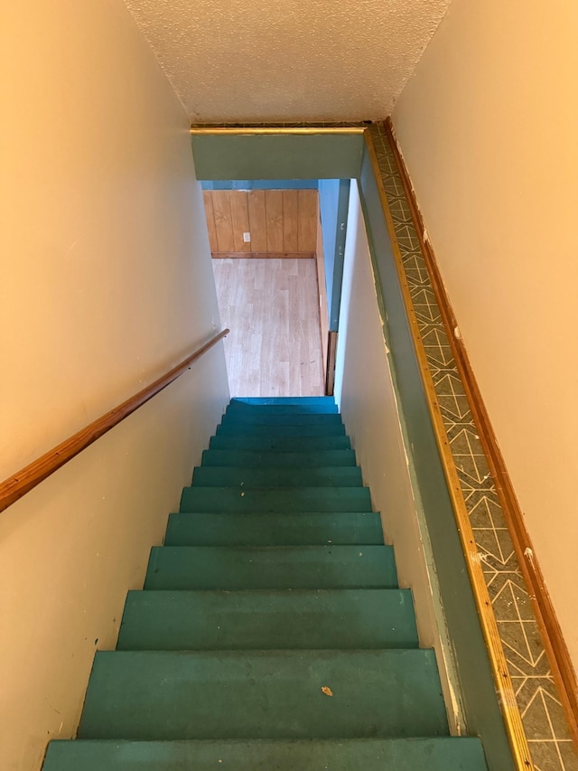 stairway with hardwood / wood-style flooring and a textured ceiling