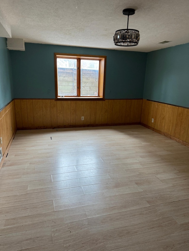 unfurnished room with a textured ceiling and light hardwood / wood-style flooring