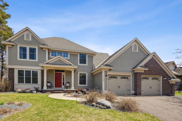 craftsman-style home with a front lawn, a porch, a garage, brick siding, and aphalt driveway
