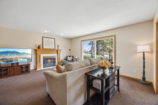 living room with a tile fireplace, baseboards, carpet floors, and a textured ceiling