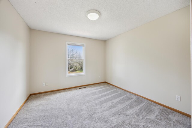 carpeted spare room with baseboards and a textured ceiling