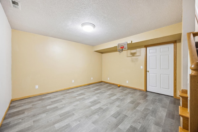 empty room featuring light wood-type flooring, baseboards, visible vents, and a textured ceiling