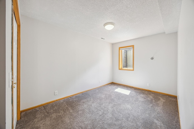 carpeted empty room featuring a textured ceiling and baseboards
