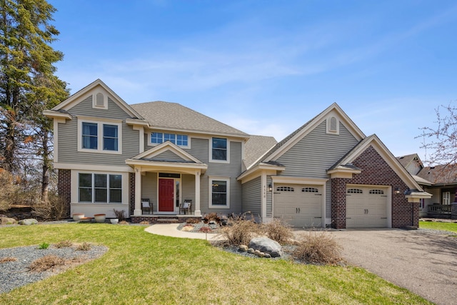 craftsman-style home with a front lawn, brick siding, aphalt driveway, and a garage