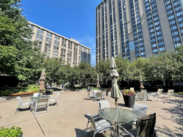 view of home's community featuring a view of city, a patio, and outdoor dining area