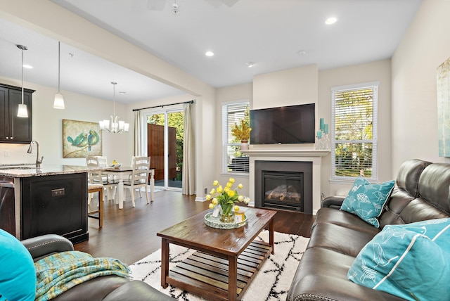 living room featuring dark wood-type flooring, a chandelier, and sink