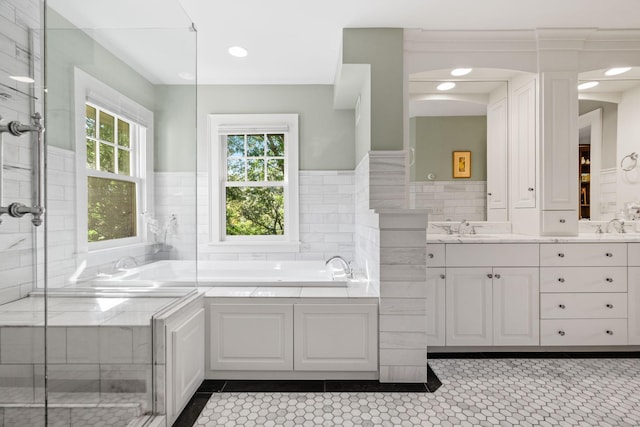 bathroom with tile patterned floors, vanity, a bathtub, and tile walls