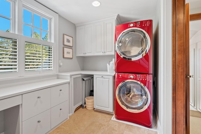 clothes washing area featuring stacked washer and clothes dryer and cabinets