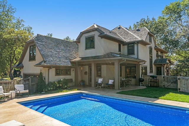 rear view of property with a fenced in pool and a patio